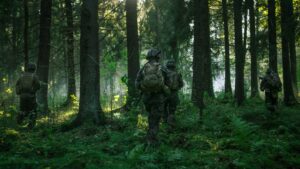 Fully Equipped Soldiers Wearing Camouflage Uniform Attacking Enemy, Rifles Ready to Shoot. Military Operation in Action, Squad Running in Formation Through Dense Smokey Forest. Back View Footage.