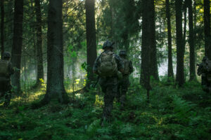 Fully Equipped Soldiers Wearing Camouflage Uniform Attacking Enemy, Rifles Ready to Shoot. Military Operation in Action, Squad Running in Formation Through Dense Smokey Forest. Back View Footage. Fully Equipped Soldiers Wearing Camouflage Uniform Attacking Enemy, Rifles Ready to Shoot. Military Operation in Action, Squad Running in Formation Through Dense Smokey Forest. Back View Footage.