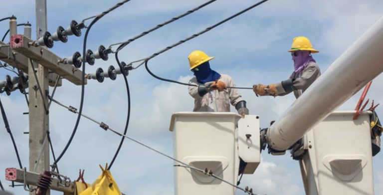 Utility Linemen in two crane lifters working on power lines
