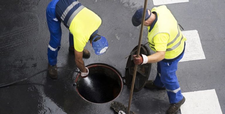 Two utility workers working on underground utilities