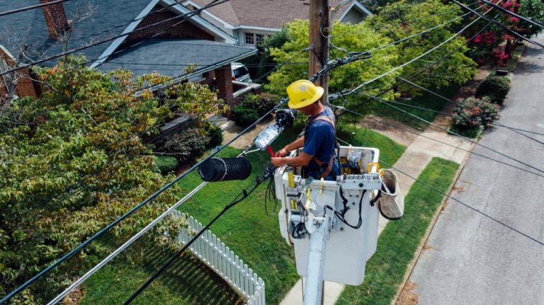 Utility worker in crane lift working on a power line